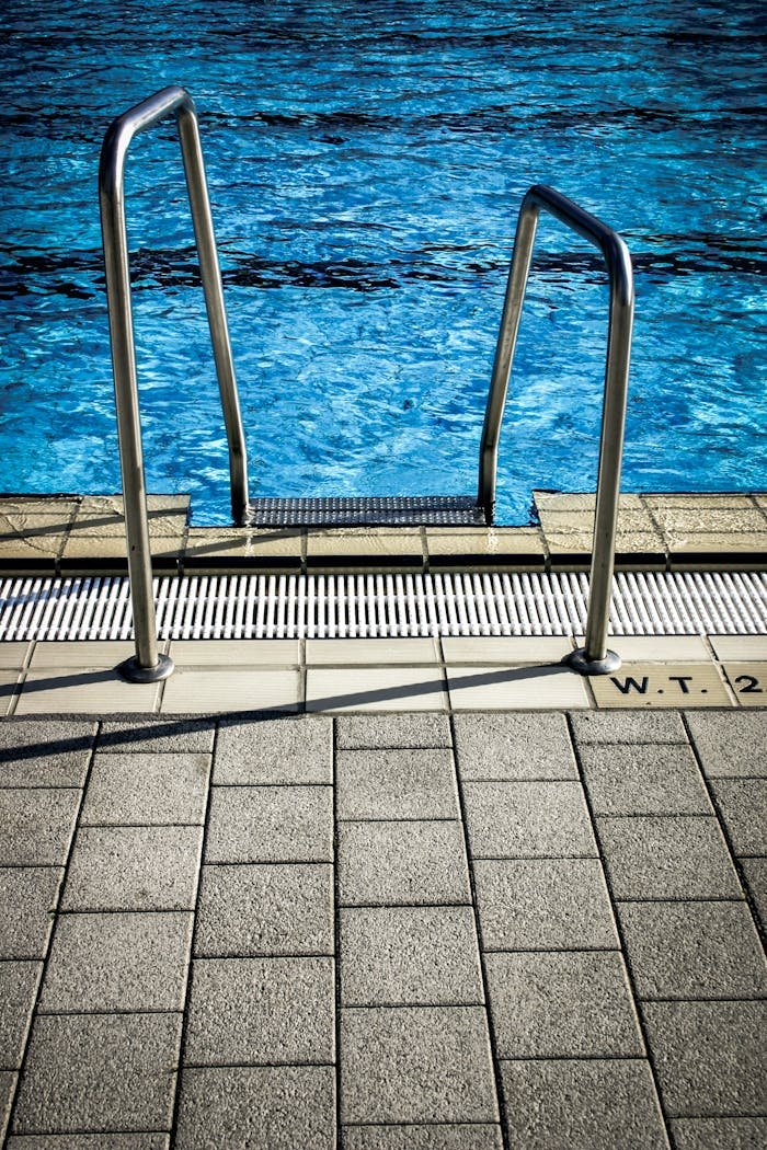 Close-up of a pool ladder with blue water, showcasing a serene outdoor setting.